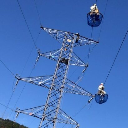 鉄塔に架かる電線で作業する写真