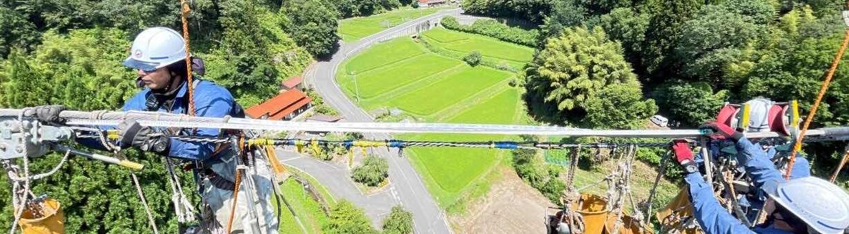 高所で電線作業をする写真